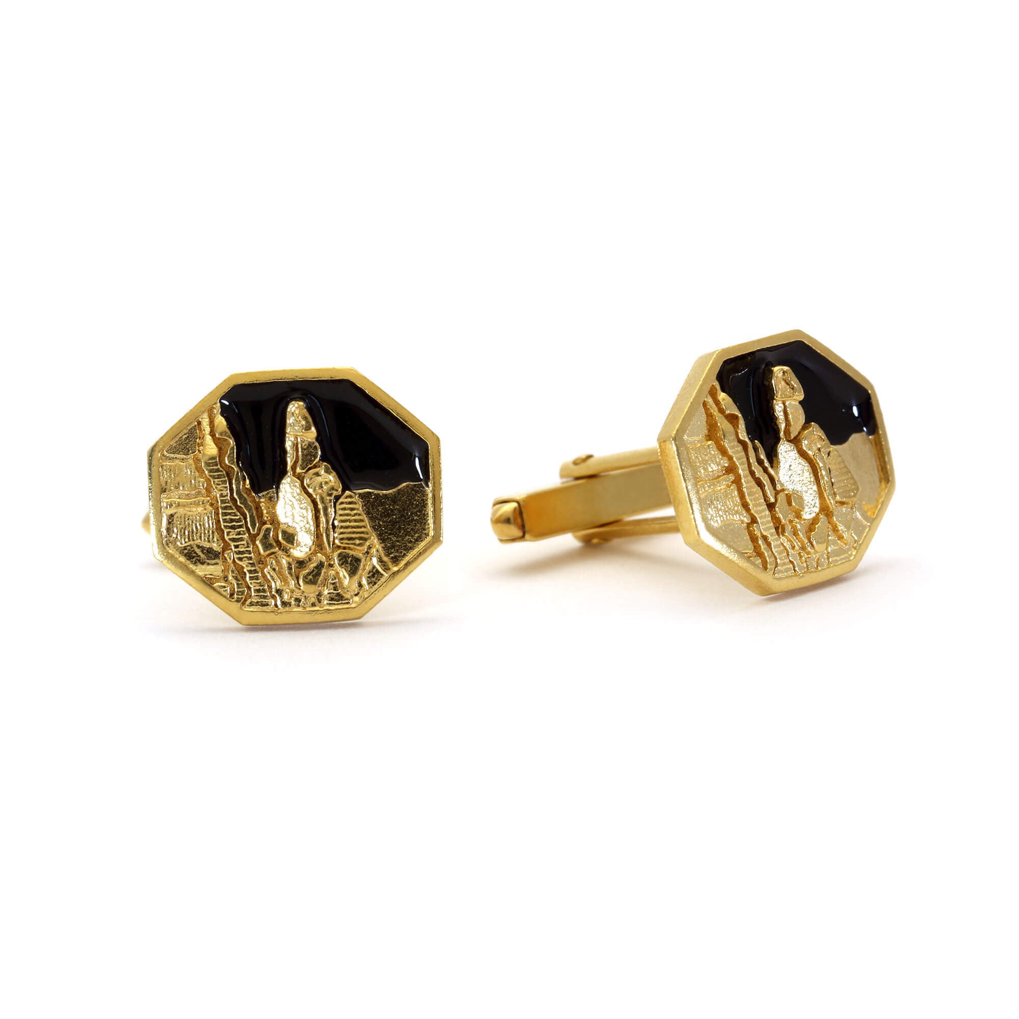 A pair of cufflinks picturing Napes Needle in gold against a black enamel sky