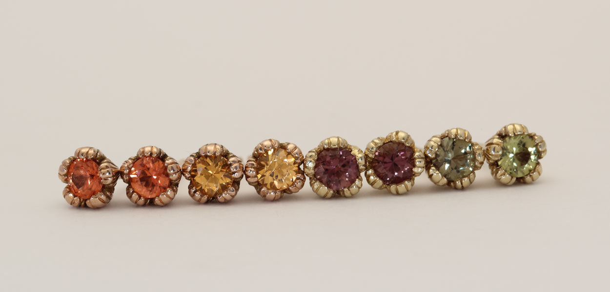 A line up of pastel sapphire stud earrings, multi coloured gemstones set in solid yellow and rose gold