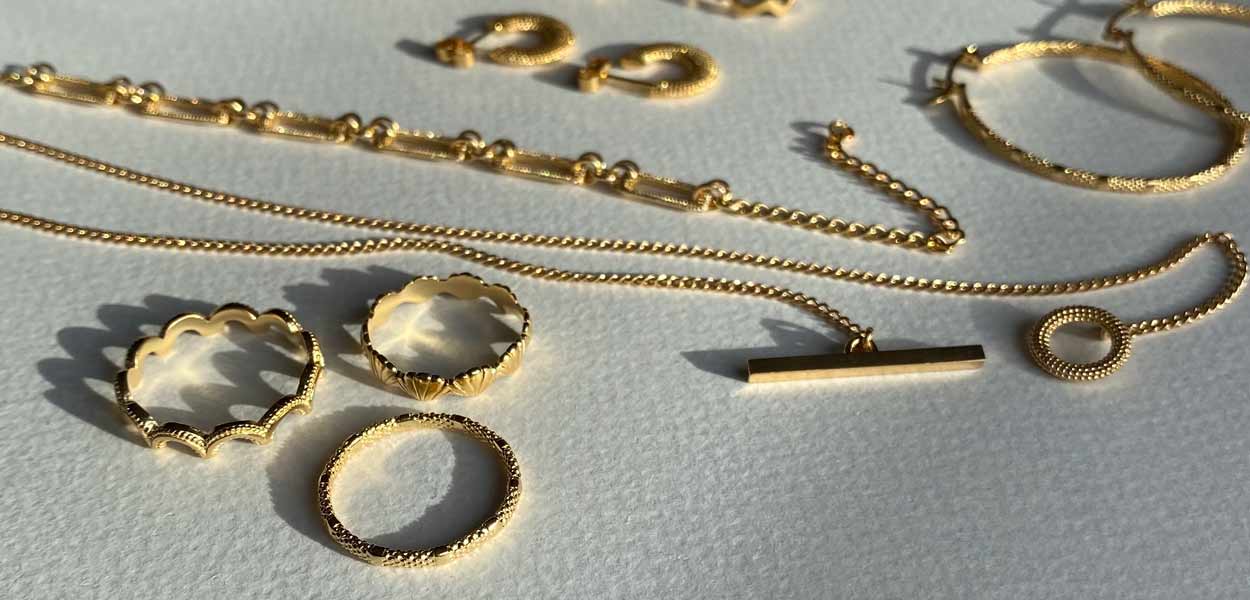 A beautiful textured selection of freshly plated gold handmade pieces of jewellery all in stock and shining in the sunlight 