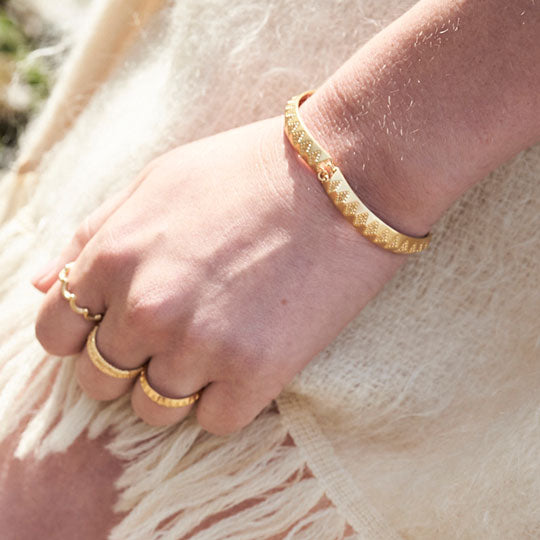 Handmade gold bracelet worn by model on sunny day