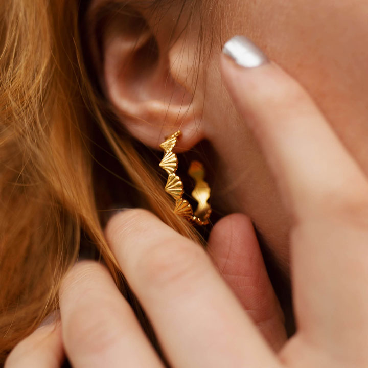 Handcrafted fairmined gold shell hoop earrings worn by model