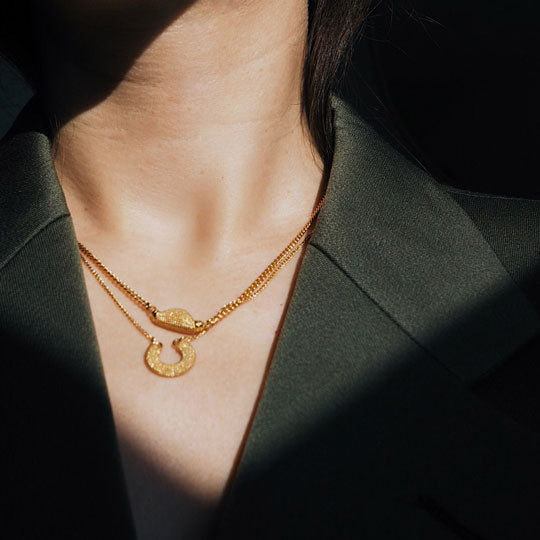 2 gold necklaces on model wearing black blazer
