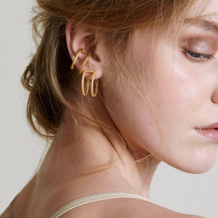 a pair of gold double hoop earrings on model
