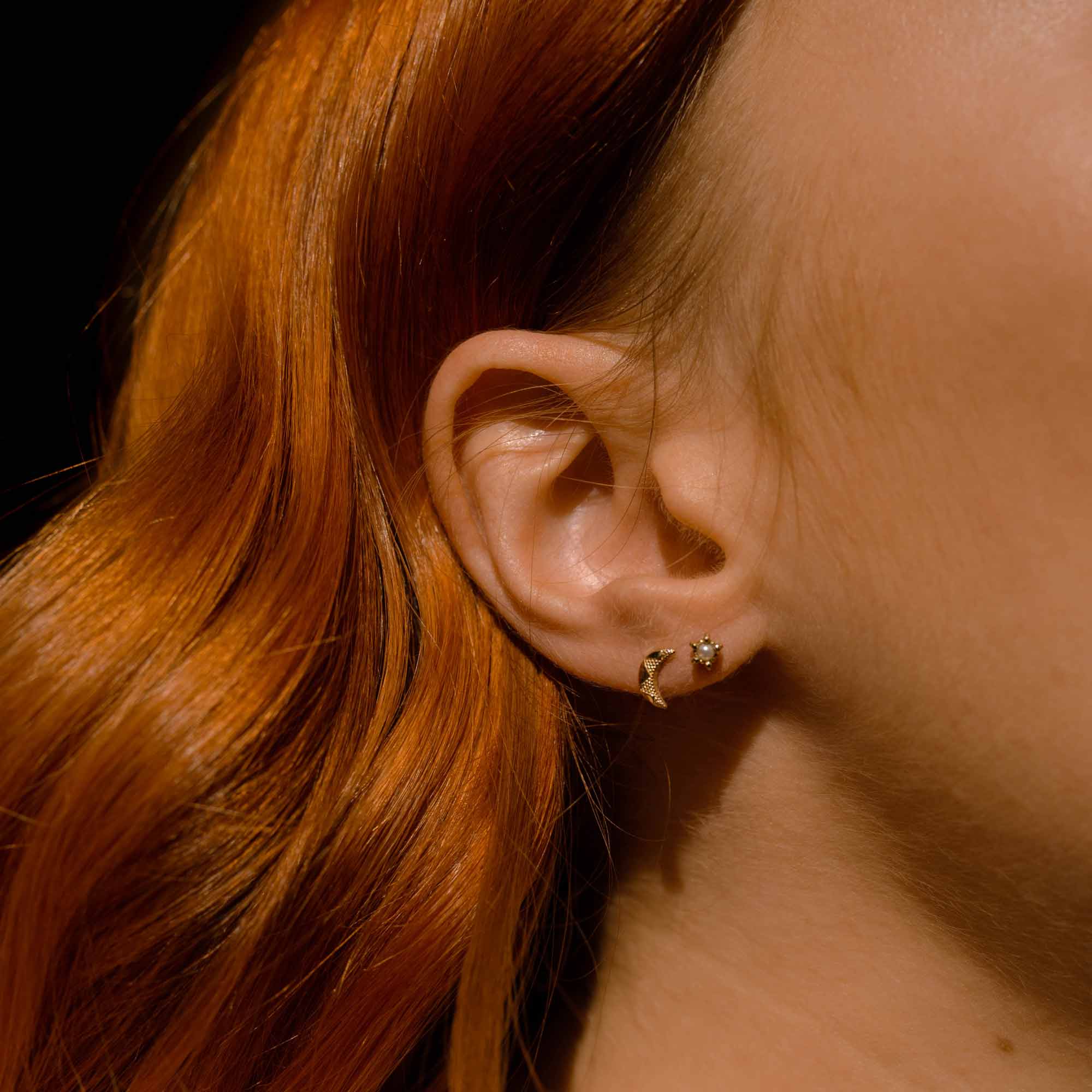 Model wears tiny crescent moon stacked up with tiny pearl gold stud