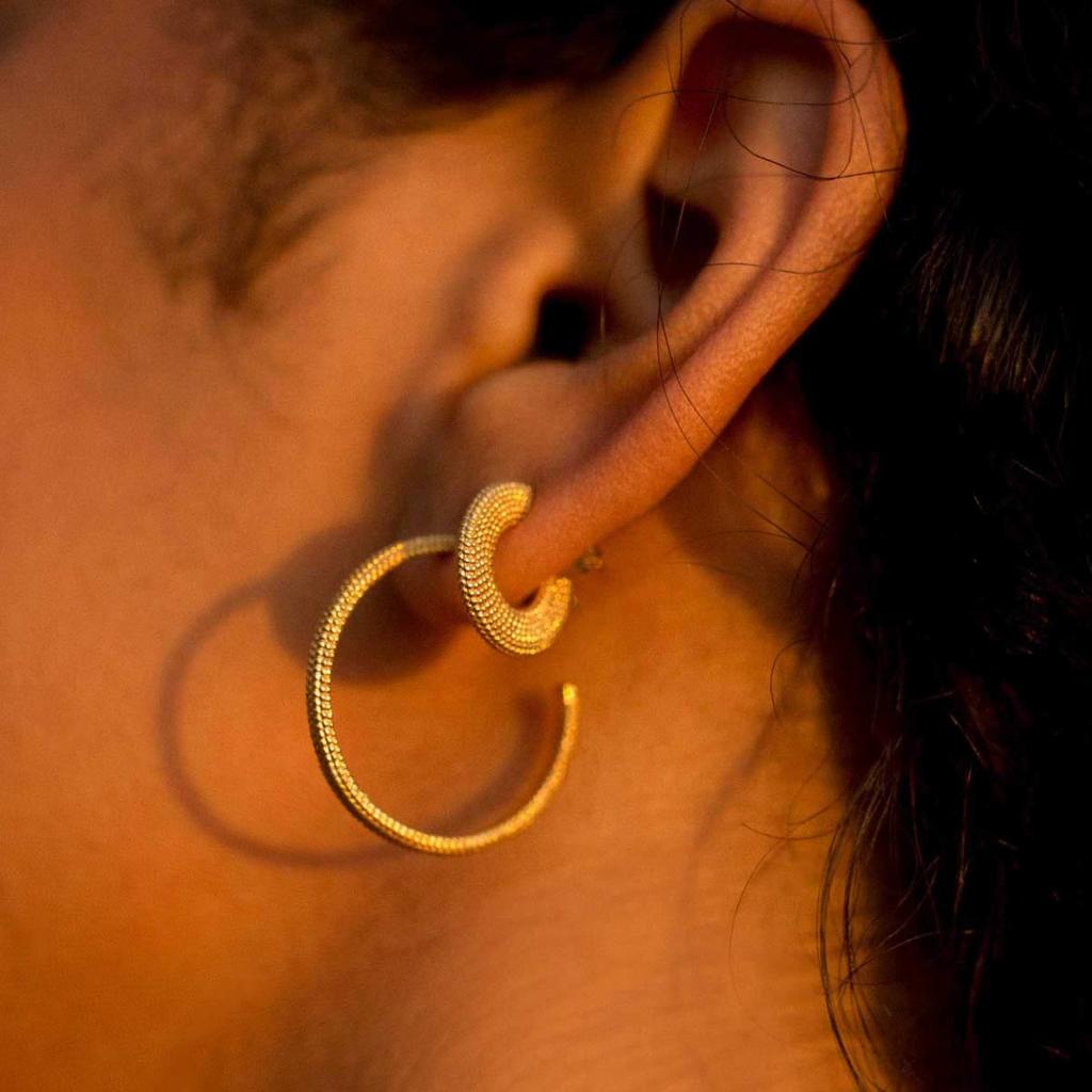 Textured gold huggie hoop earring and large hoop earring on ear