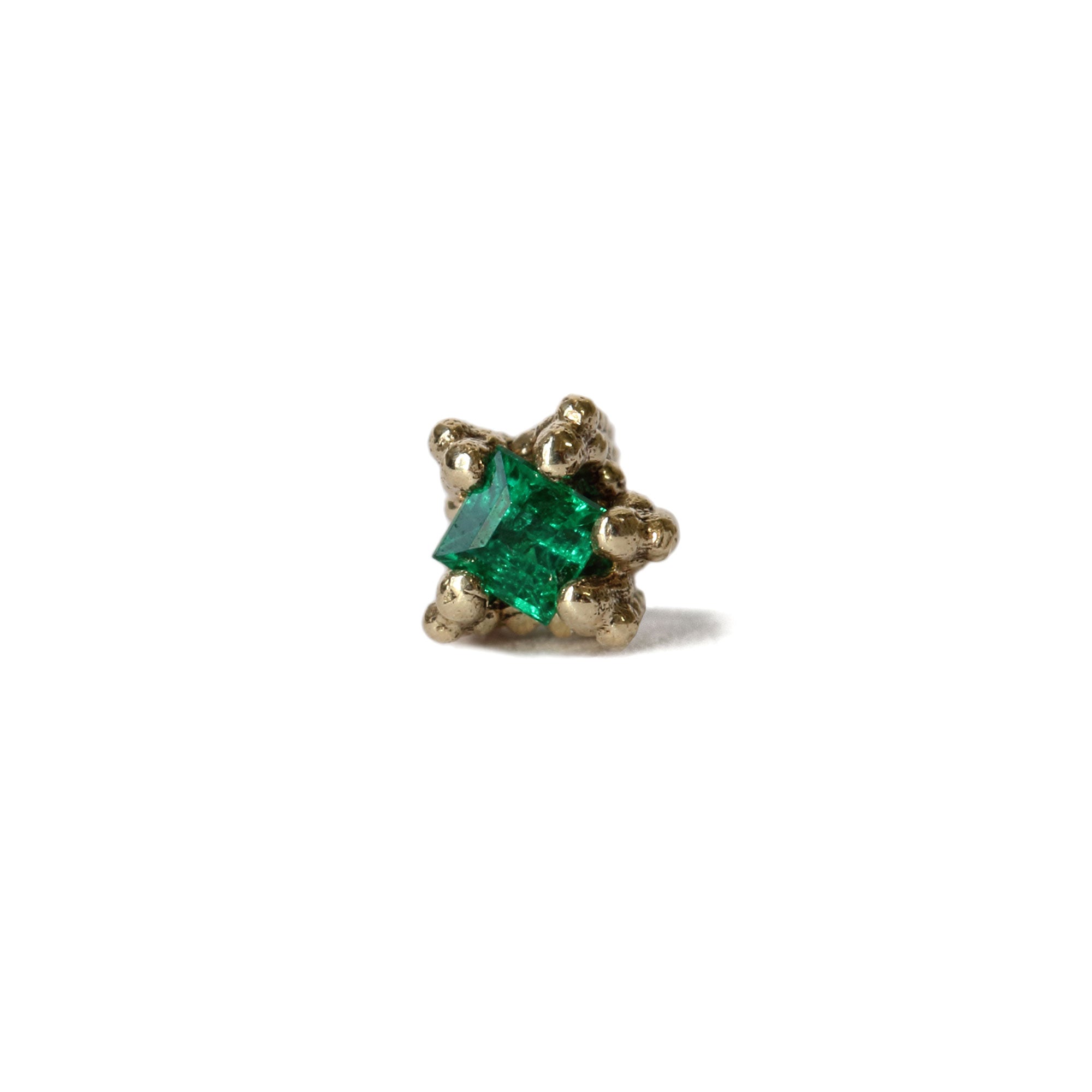 Tiny emerald set gold stud earring on white background