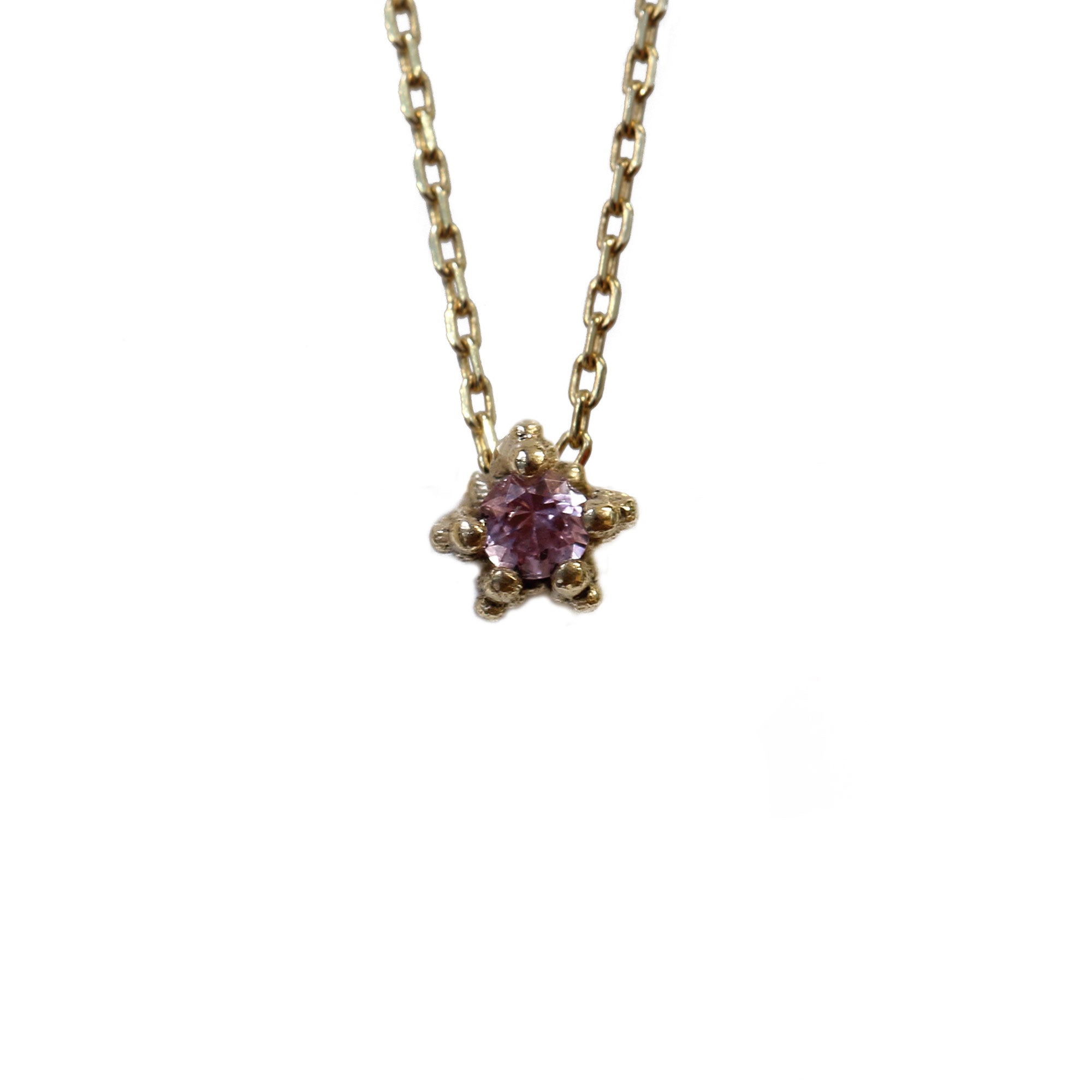 Tiny pink sapphire set textured gold necklace on white background