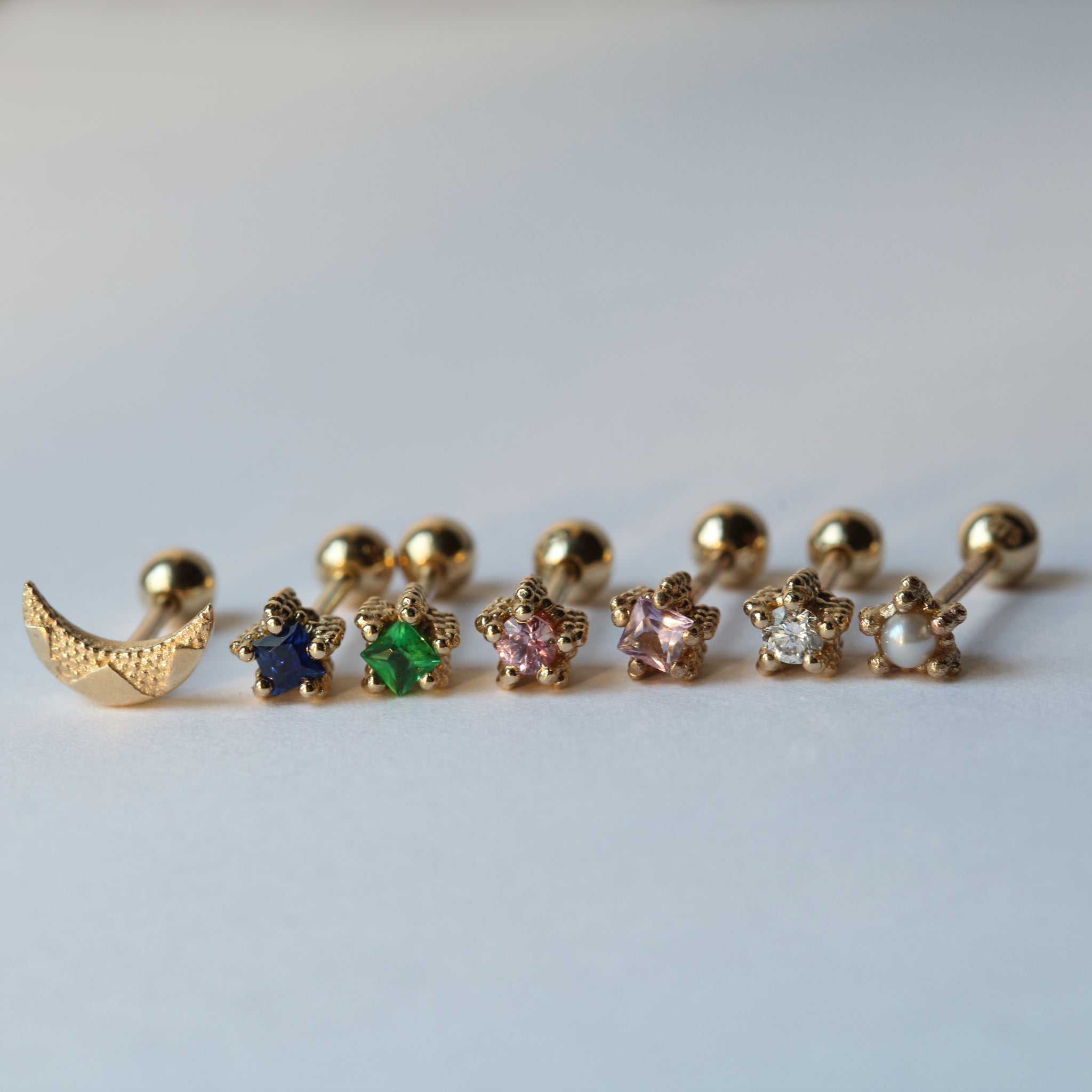 Multi coloured tiny stone set gold earrings in a row