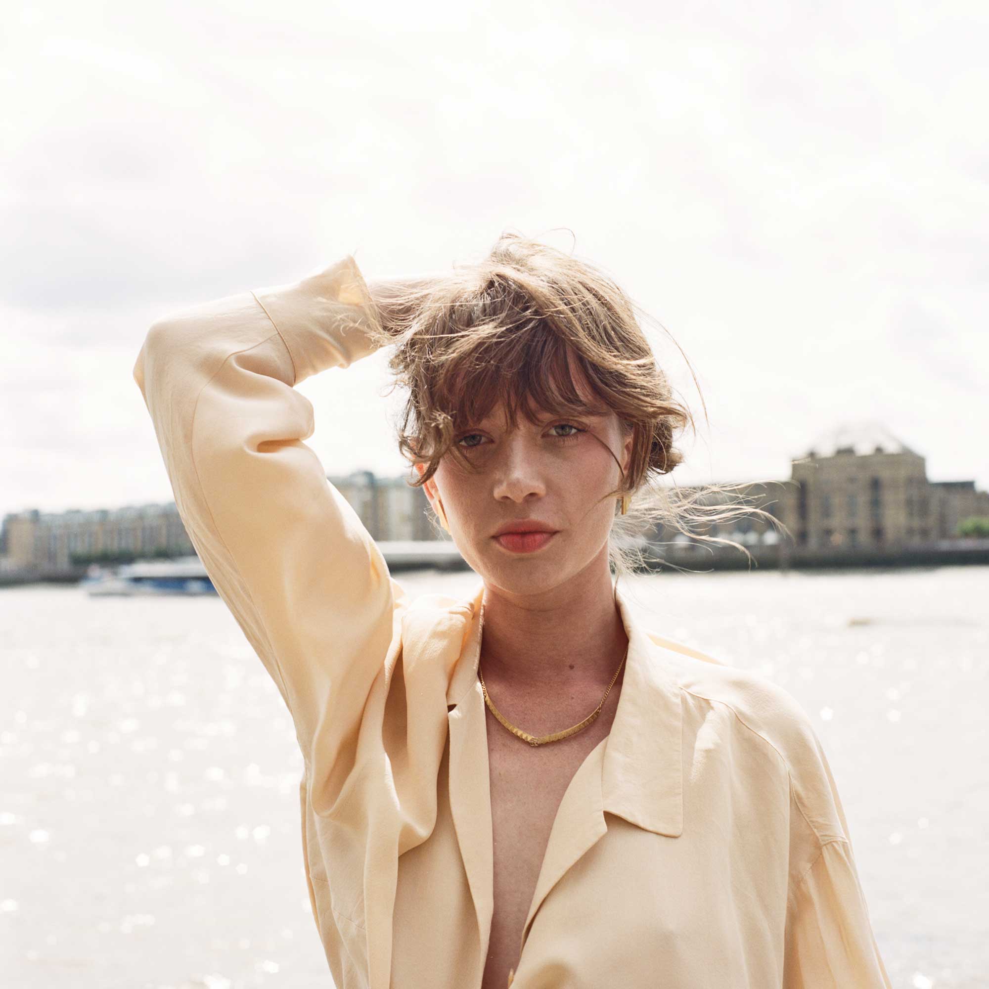 Model wearing Chasm yellow necklace by river Thames