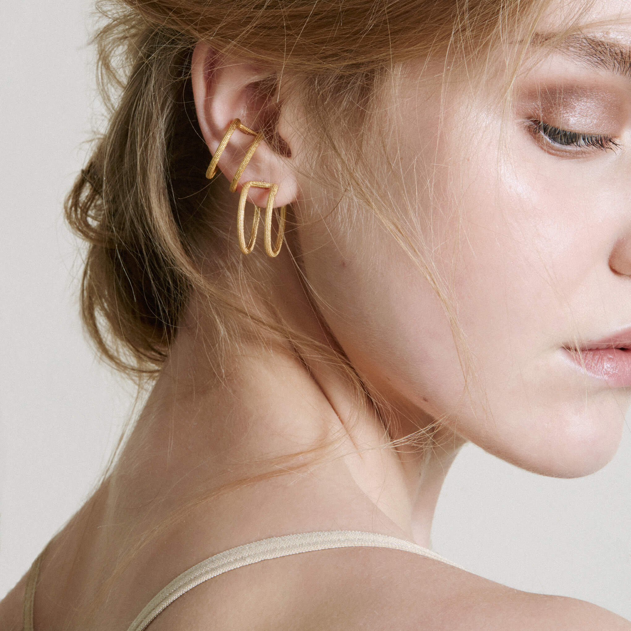 Model looking over shoulder wearing gold double hoop earrings