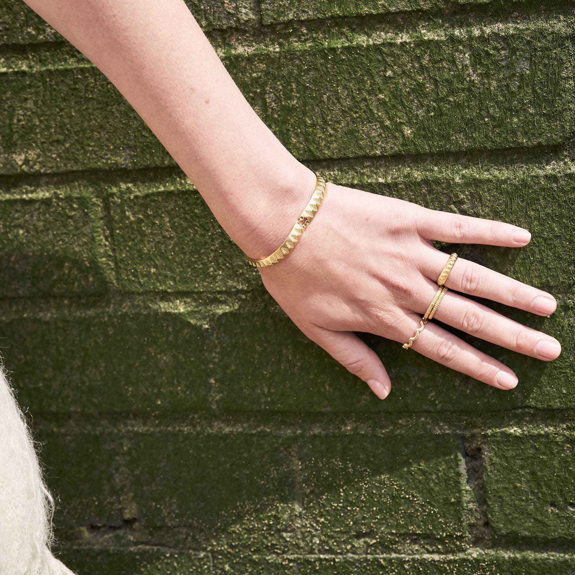 Magma Wiggle Yellow Gold Ring on model next to green wall
