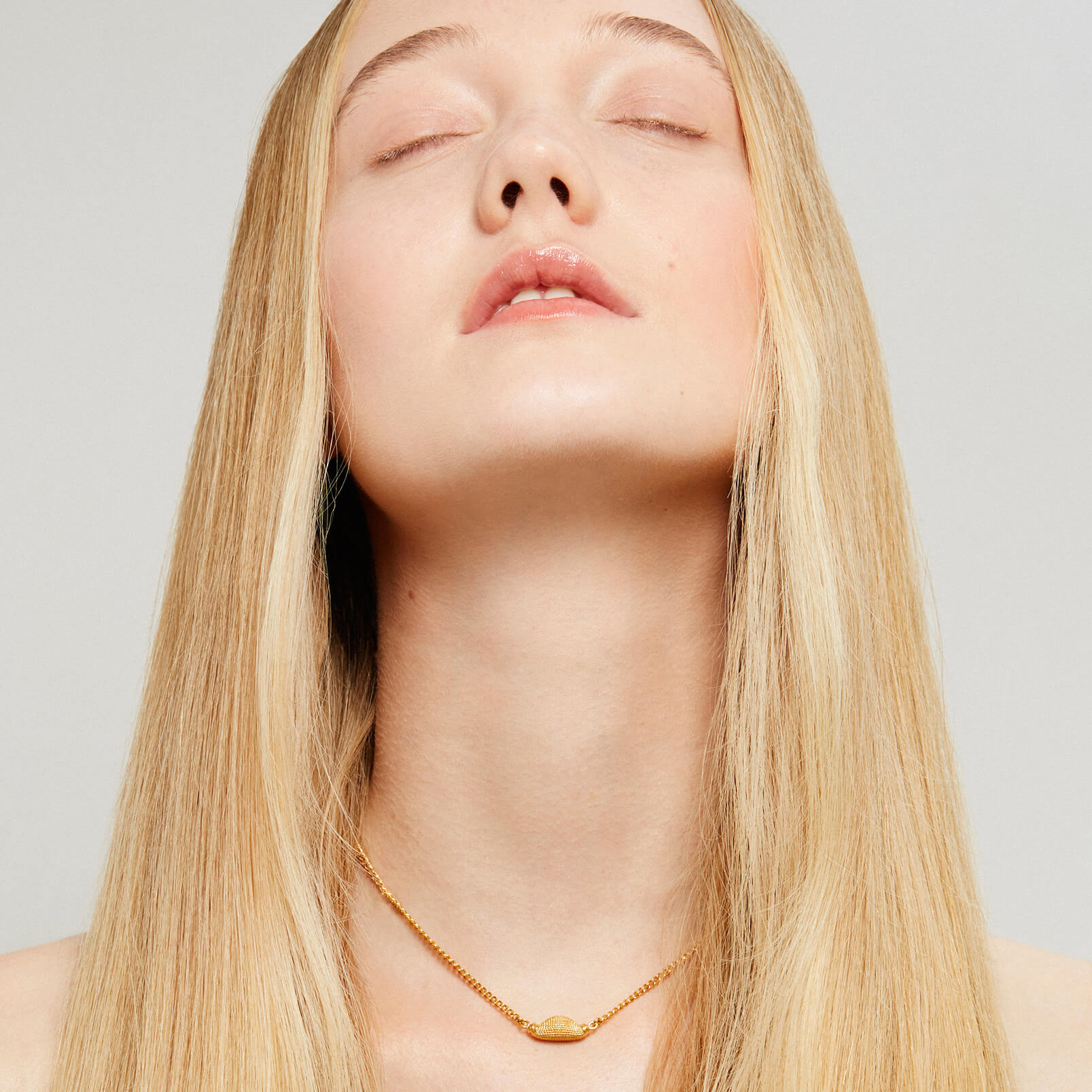 Model wearing a short gold necklace with nugget design