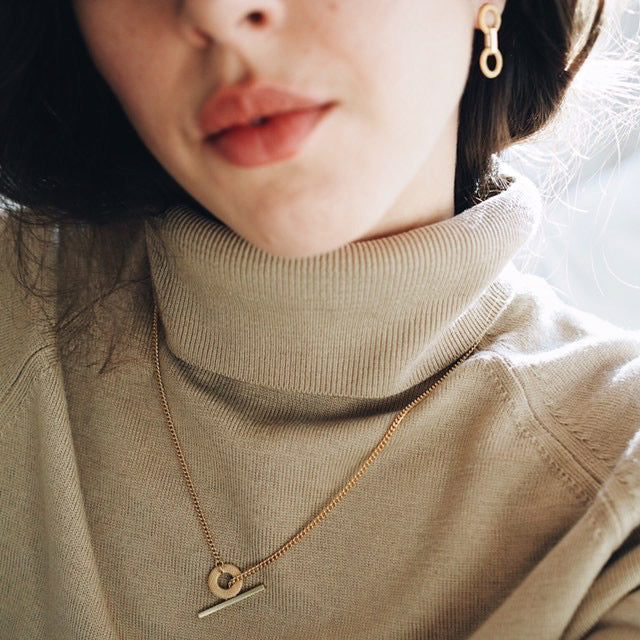 Model in roll neck jumper wearing gold earrings and necklace