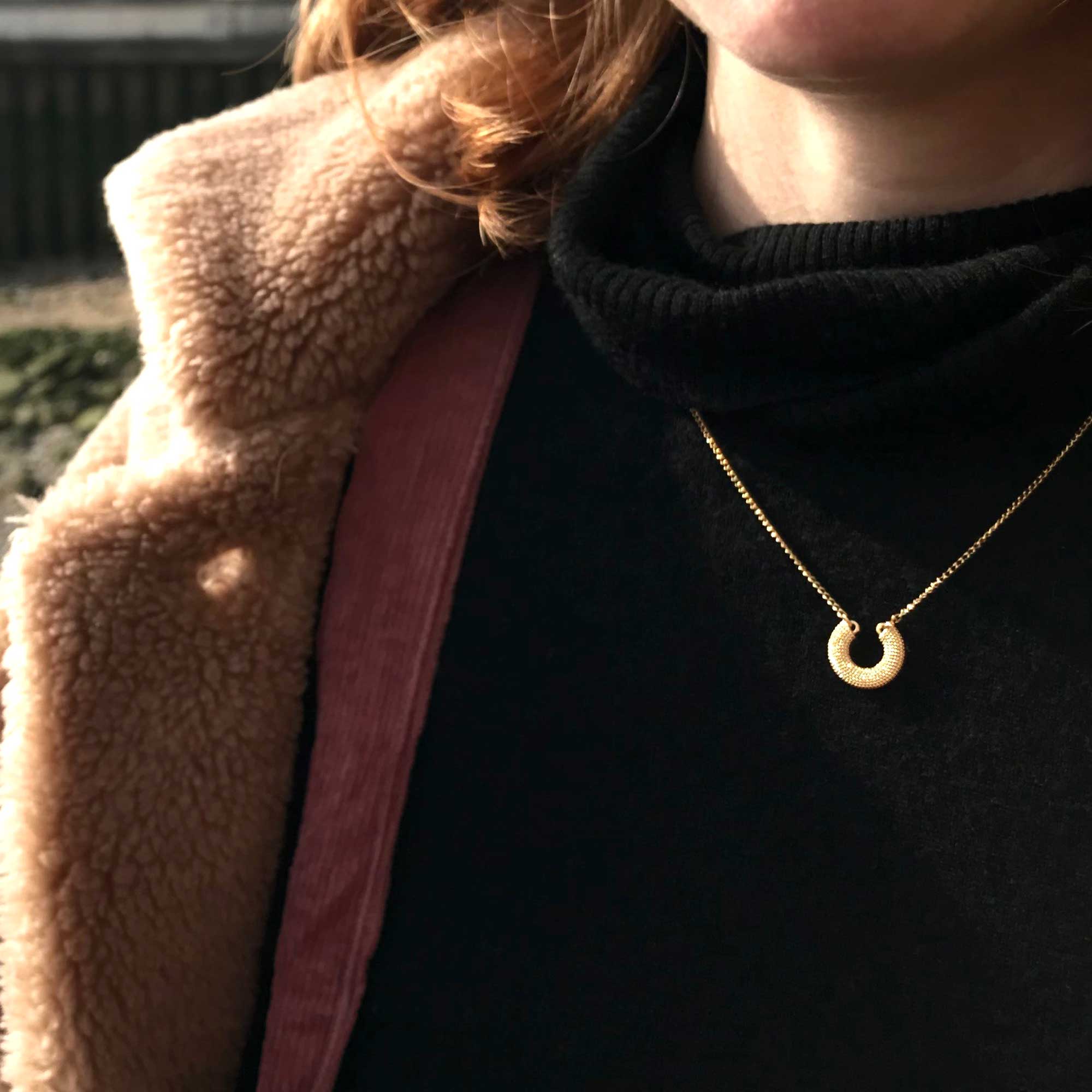 Gold textured horseshoe necklace on model